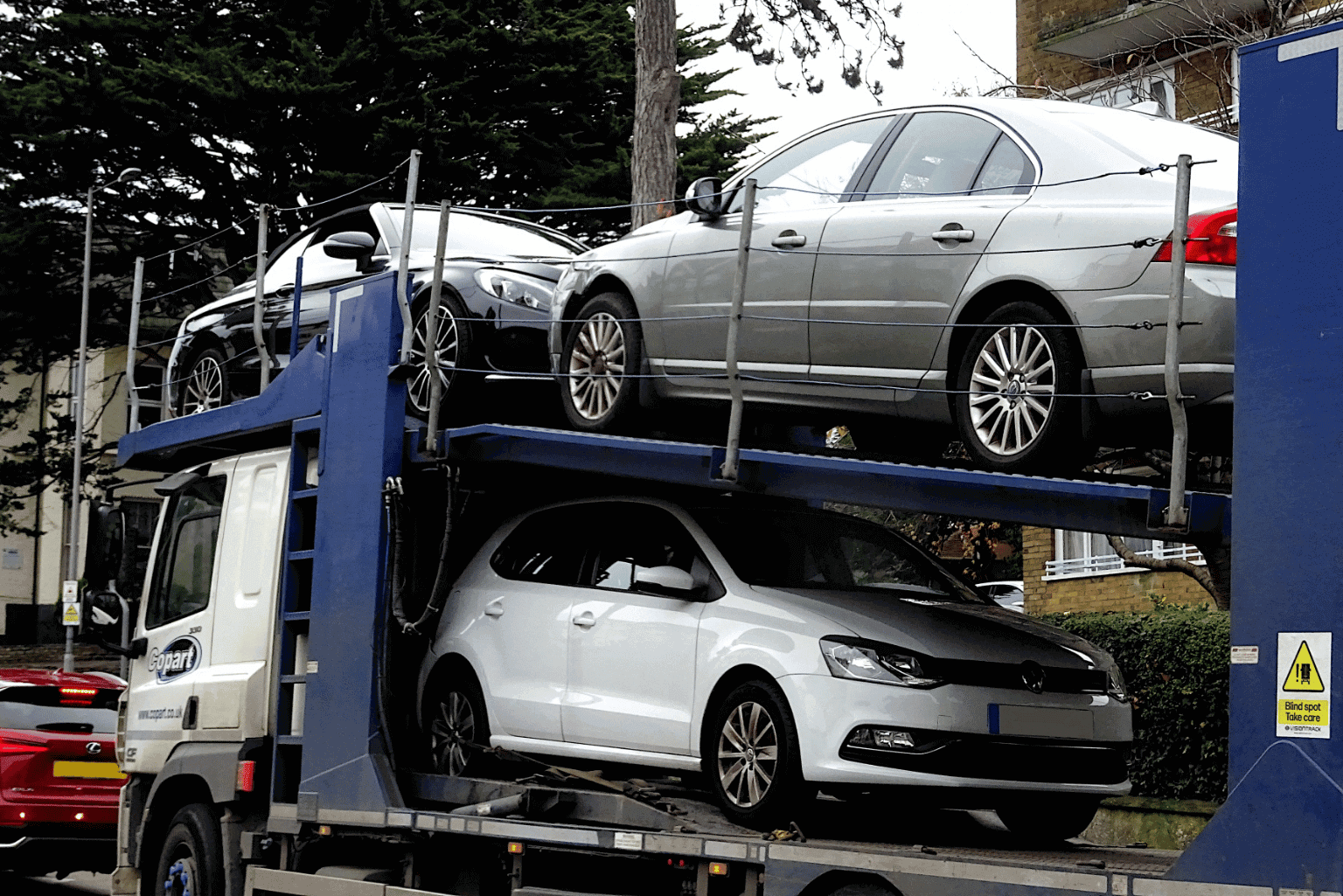 Two silver cars loaded on a blue car transport truck.