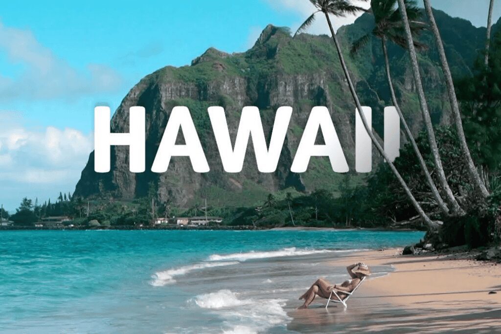 Tropical beach scene in Hawaii with palm trees and mountain backdrop.