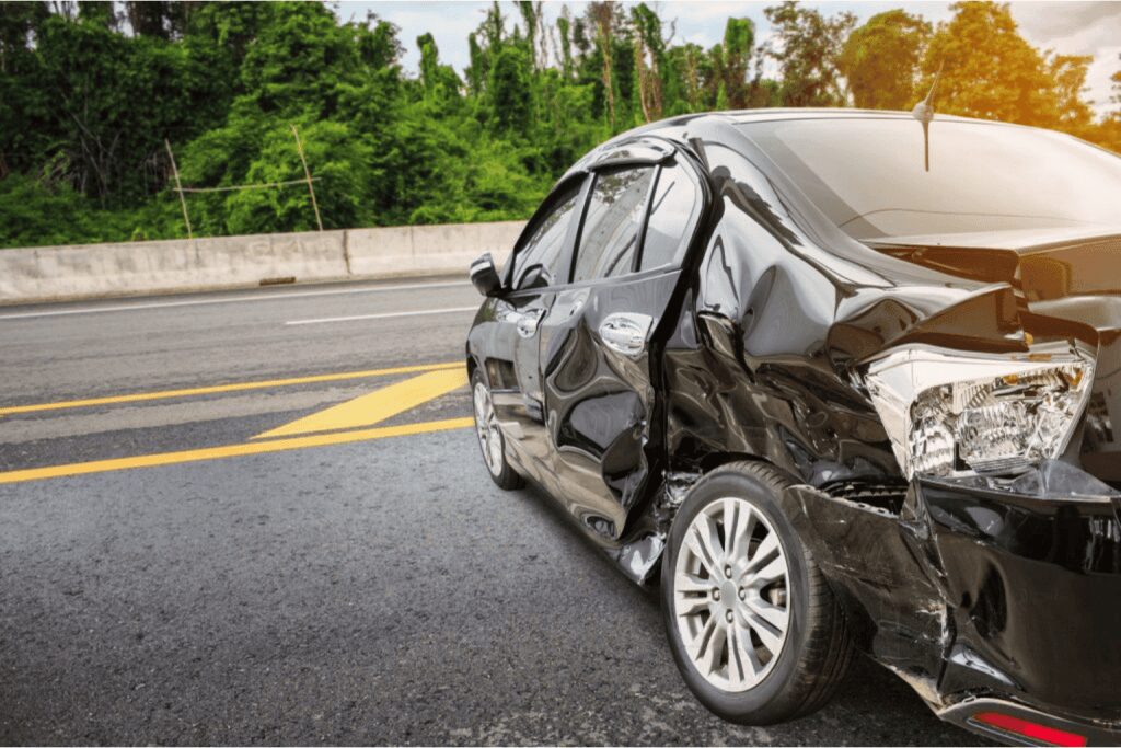 Damaged black car after an accident on the road.