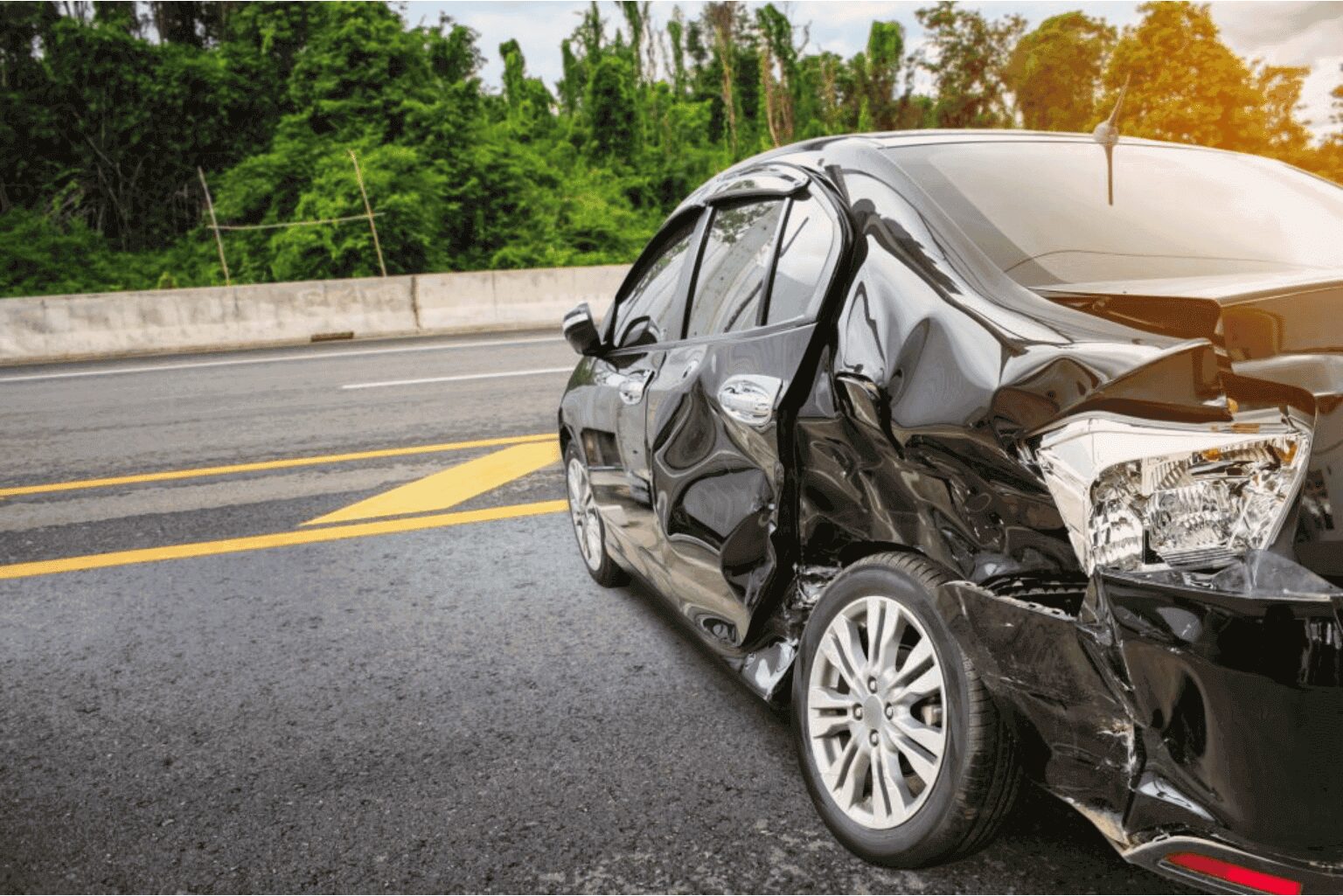 Damaged black car after an accident on the road.