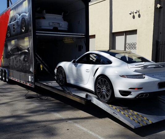 A white sports car being loaded into a transport truck.