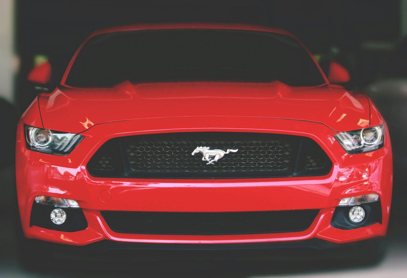 Front view of a red Ford Mustang showcasing its iconic grille and emblem.